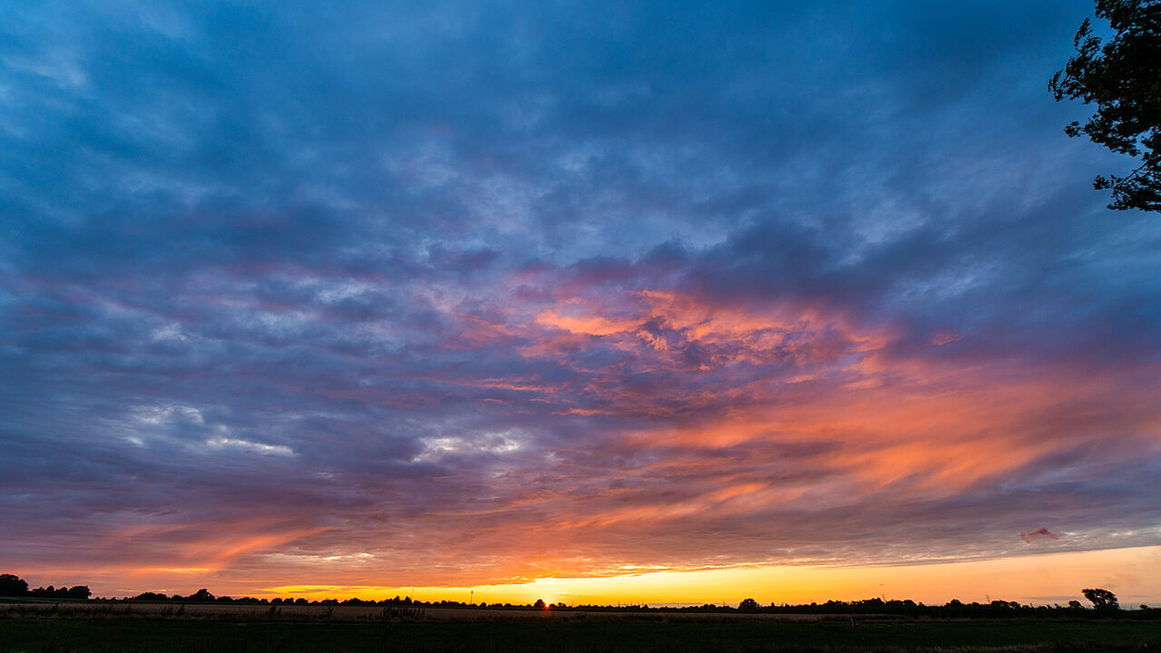 Leuchtender Sonnenuntergang unter einem weiten Wolkenhimmel bei Meerbusch